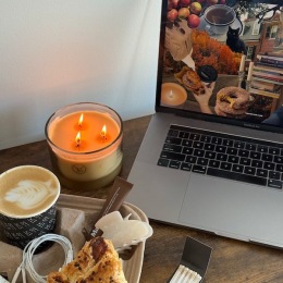 a table with a laptop, candle and drink
